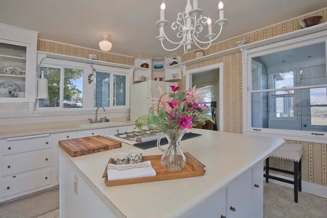 a kitchen with granite countertop a refrigerator a sink dishwasher a stove a dining table and chairs with wooden floor