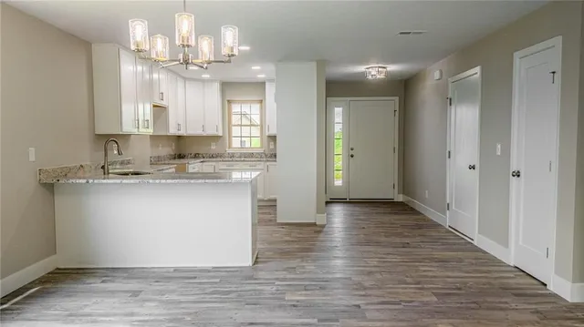 a view of a kitchen with granite countertop wooden floor and stainless steel appliances