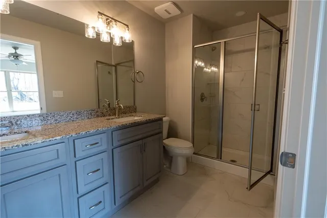 a bathroom with a granite countertop sink toilet and shower