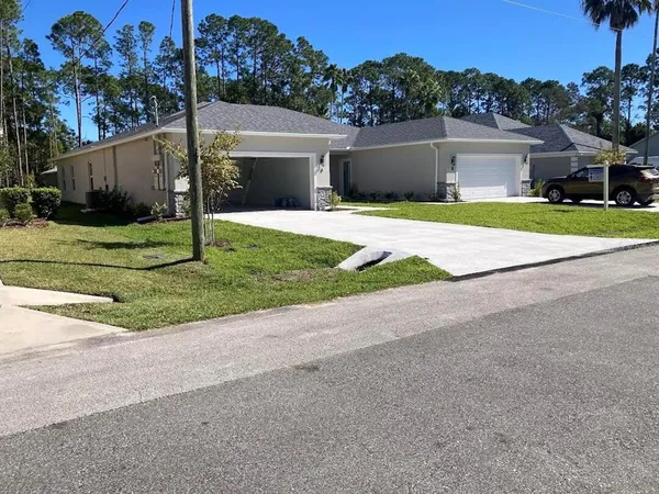 a view of a house with a yard and palm trees