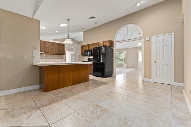 a view of kitchen with stainless steel appliances kitchen island granite countertop a refrigerator and a sink