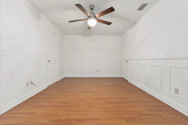 an empty room with ceiling fan and window