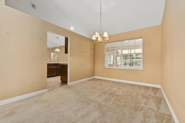 an empty room with chandelier fan and windows