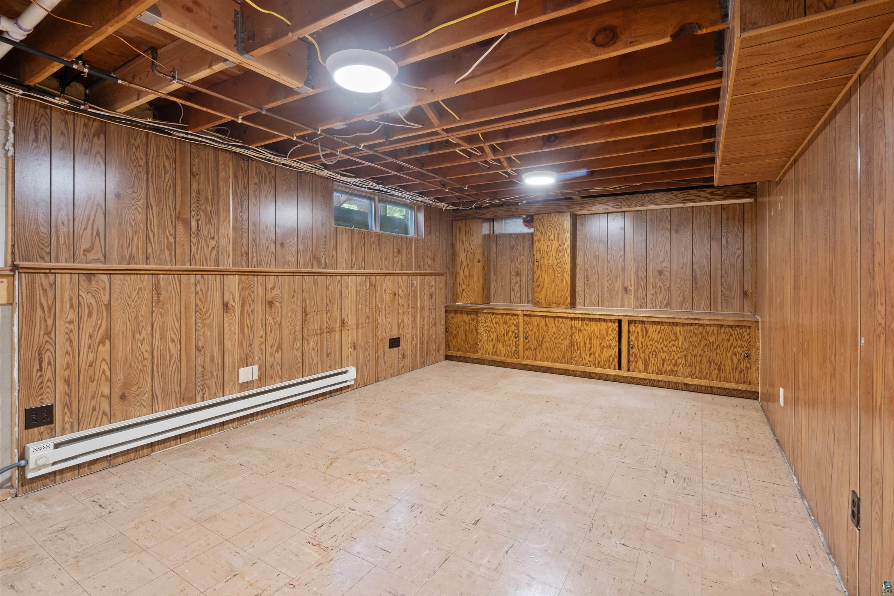 3711 Getchell Road Hermantown, MN 55811 - Photo 20 of 31 Spacious room featuring wood paneling, exposed wood beam ceiling, and durable tile flooring