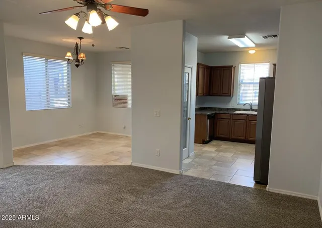 an empty room with kitchen view and a chandelier