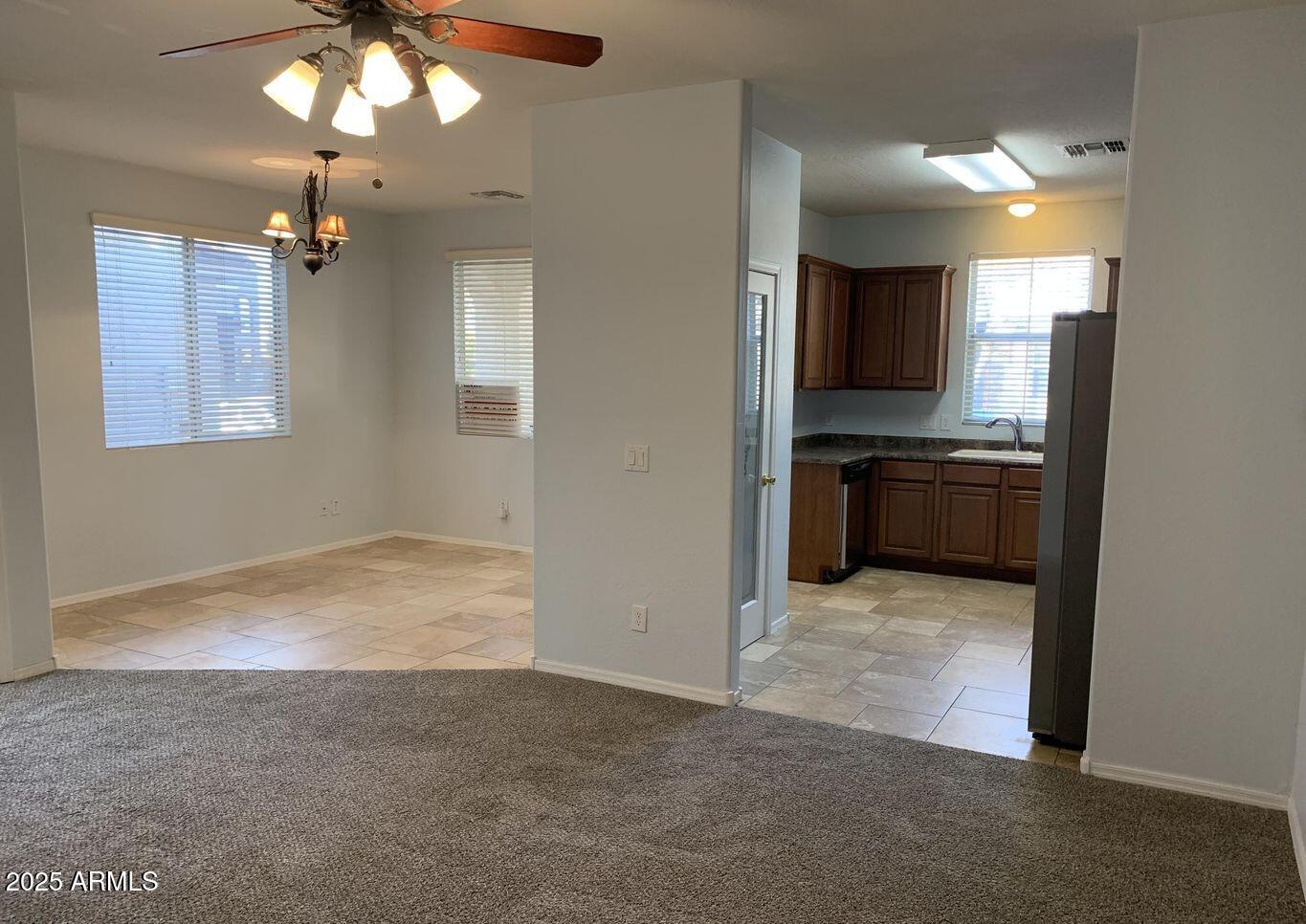 10027 West Payson Road Tolleson, AZ 85353 - Photo 3 of 18 an empty room with kitchen view and a chandelier