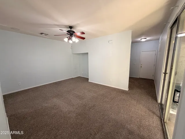 an empty room with a ceiling fan and a window