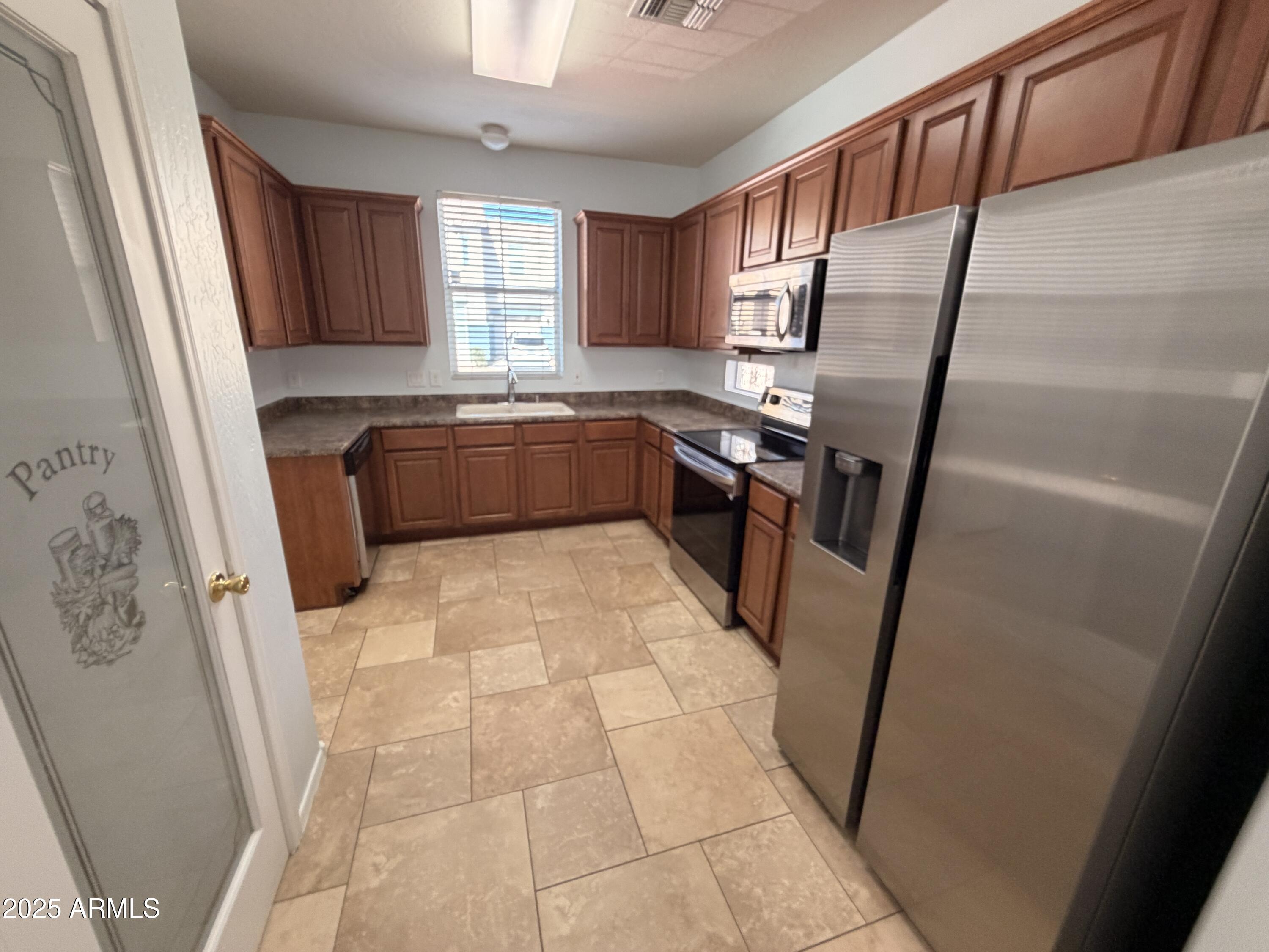 10027 West Payson Road Tolleson, AZ 85353 - Photo 5 of 18 a kitchen with granite countertop a refrigerator and a sink