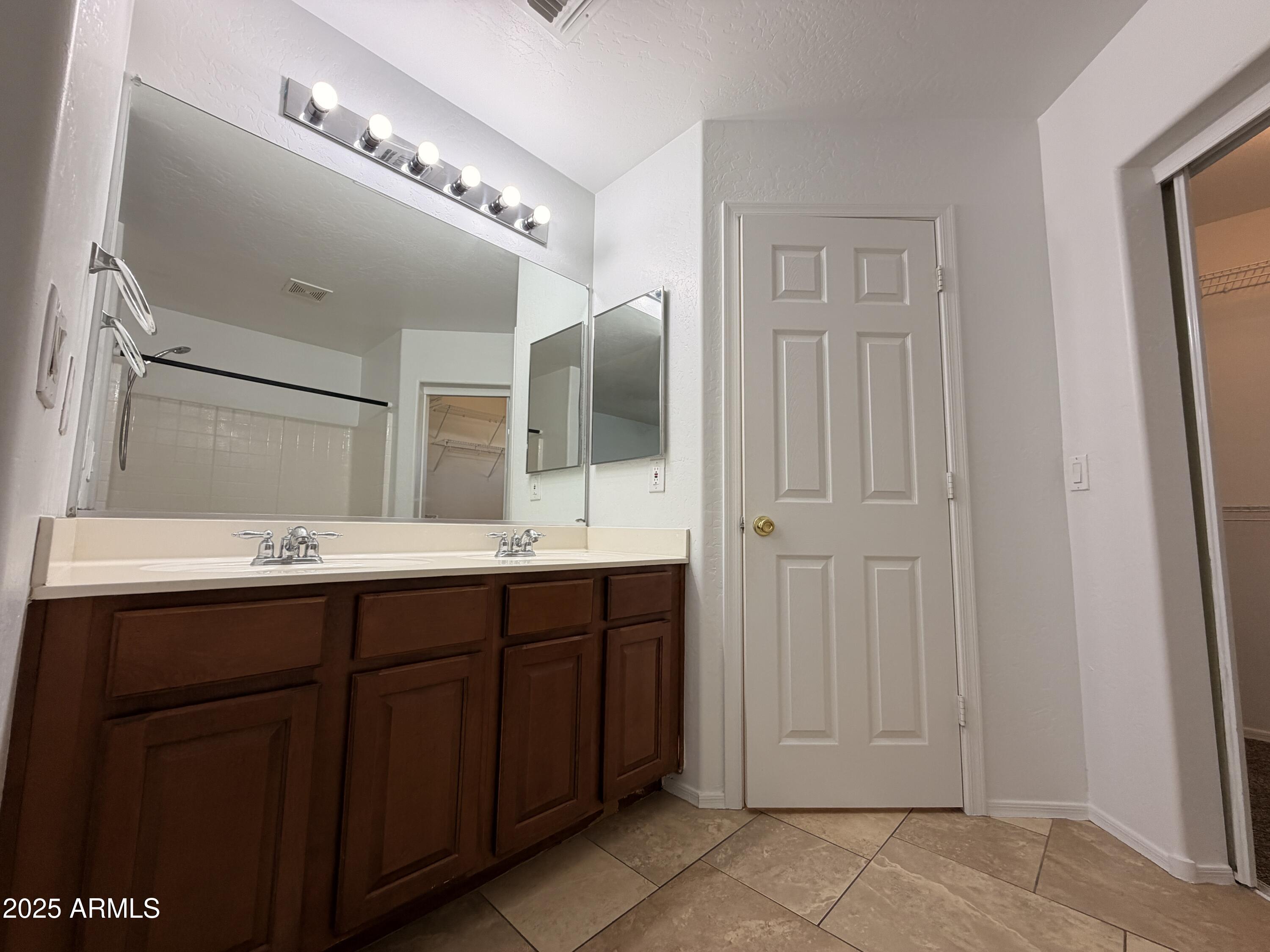 10027 West Payson Road Tolleson, AZ 85353 - Photo 9 of 18 a bathroom with a double vanity sink and mirror