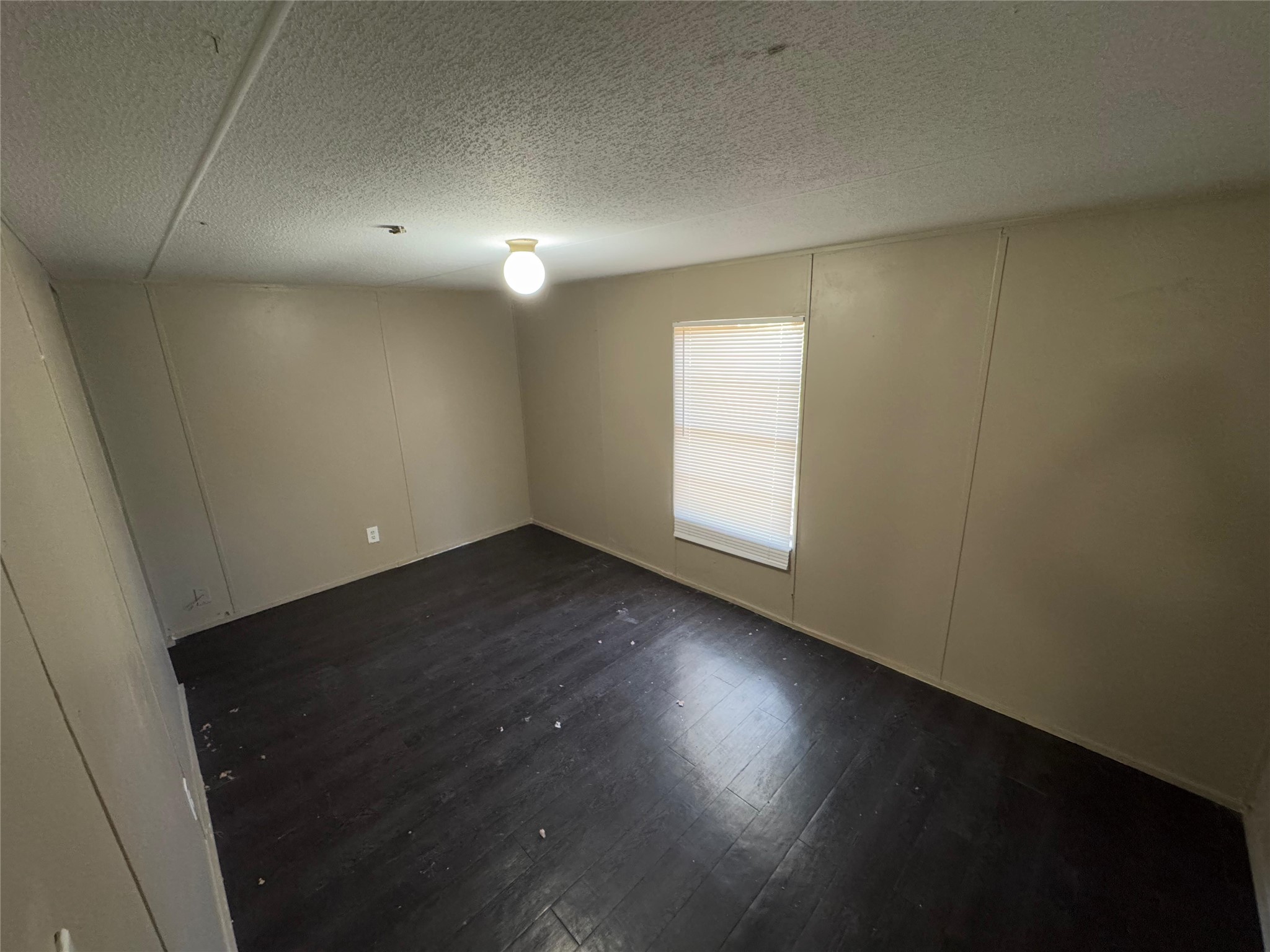8315 Burleson Manor Road, Unit B Manor, TX 78653 - Photo 11 of 15 Spare room featuring a textured ceiling, a decorative wall, and dark wood-style flooring