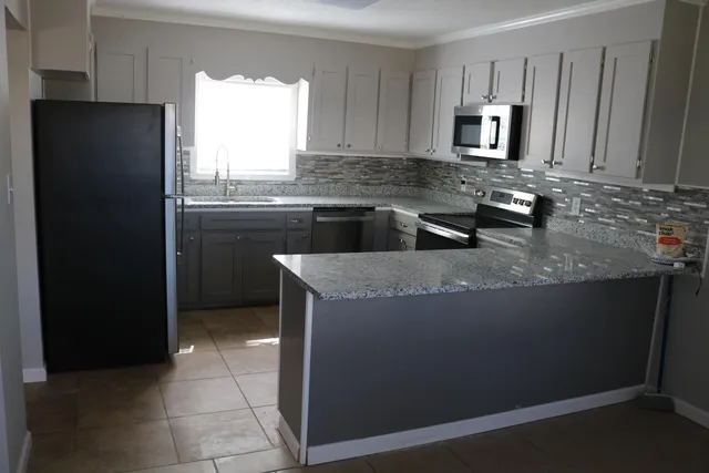 a kitchen with stainless steel appliances granite countertop a refrigerator a stove a sink and a microwave