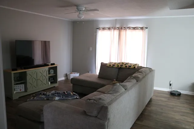 a living room with furniture a flat screen tv and a window