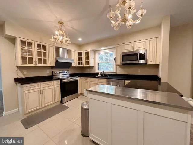 a kitchen with kitchen island granite countertop stainless steel appliances a sink a stove cabinets counter space and a window