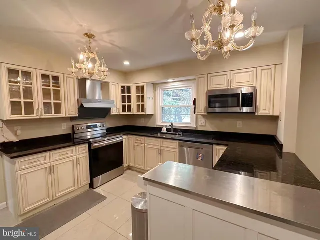 a kitchen with kitchen island granite countertop a sink stainless steel appliances and cabinets