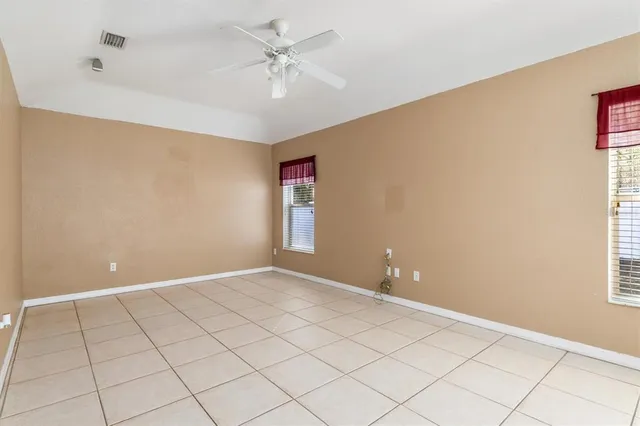 an empty room with wooden floor and fan