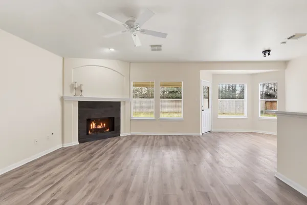 an empty room with wooden floor fireplace and windows