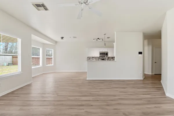 a view of kitchen and empty room with wooden floor