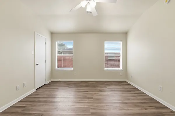 an empty room with wooden floor and windows