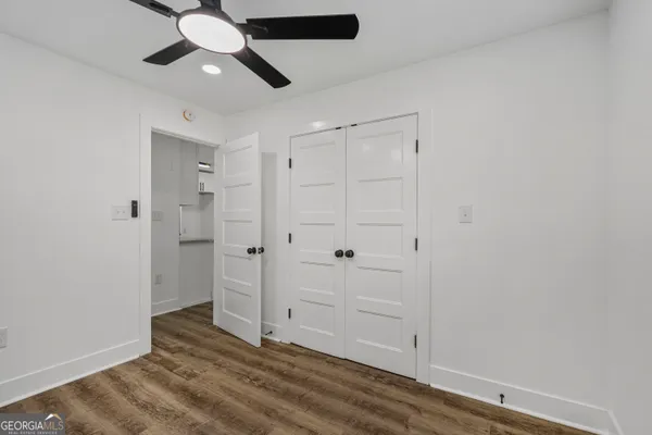 an empty room with wooden floor closet and windows