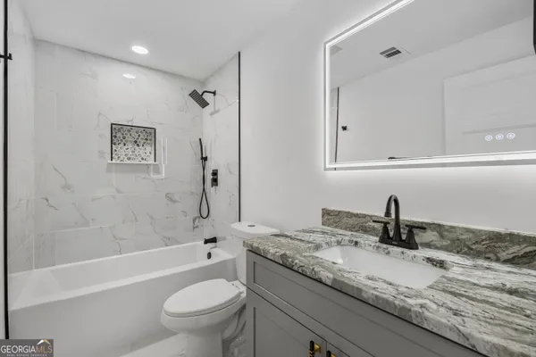 a bathroom with a granite countertop sink a toilet and a bathtub