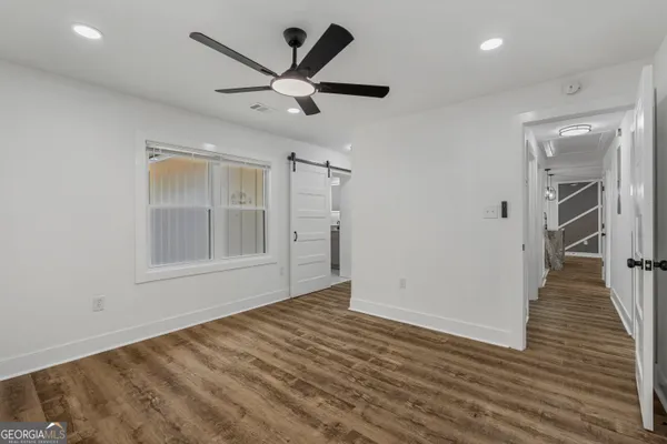 an empty room with wooden floor and a ceiling fan