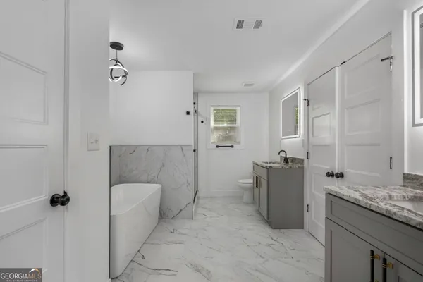 a bathroom with a granite countertop sink a toilet and shower
