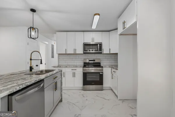 a kitchen with kitchen island granite countertop a sink stainless steel appliances and white cabinets