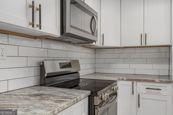 a kitchen with granite countertop white cabinets and a stove top oven