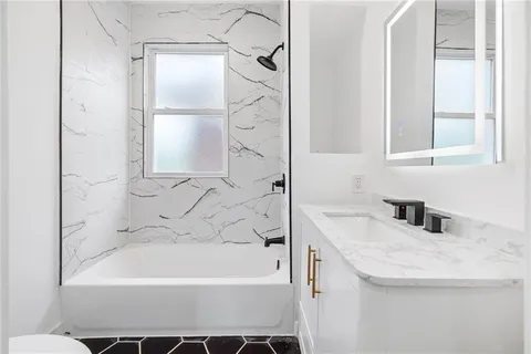 an empty room with windows fireplace and fan