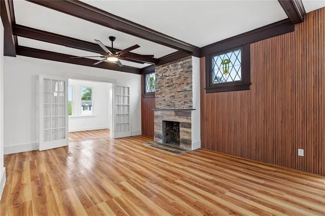 a view of an empty room with wooden floor fireplace and a window