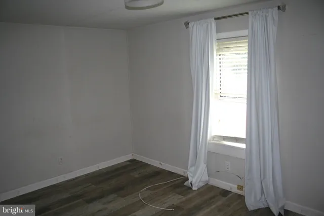 a view of an empty room and wooden floor and a window