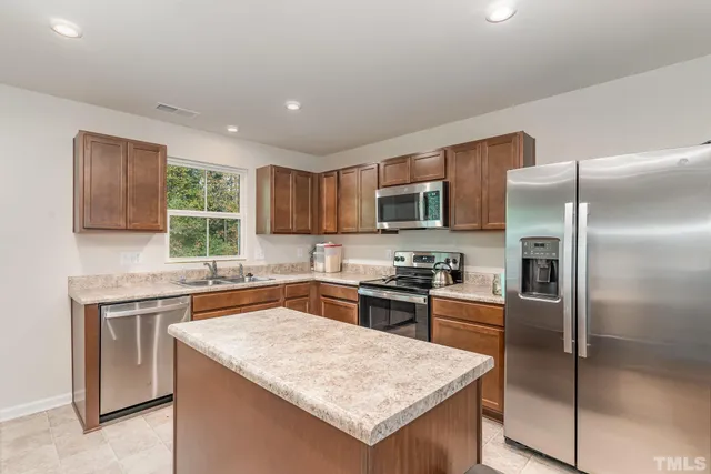 a kitchen with stainless steel appliances granite countertop a refrigerator stove microwave and sink