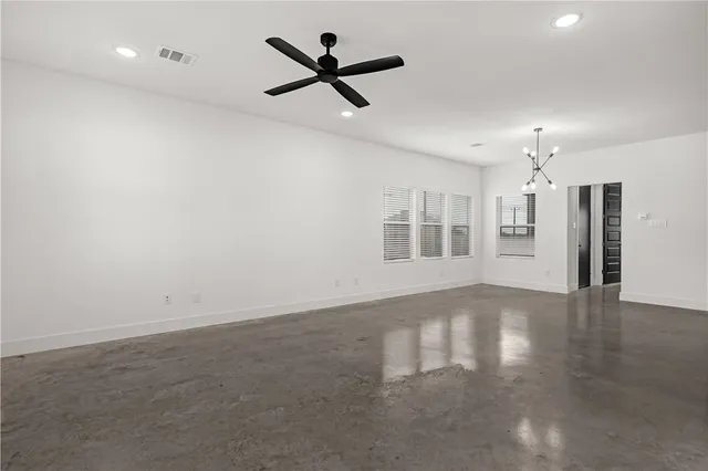 an empty room with wooden floor ceiling fan and windows