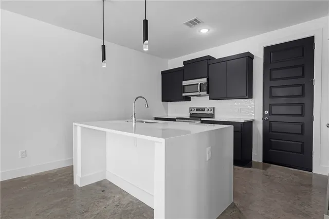 a kitchen with kitchen island a sink stainless steel appliances and cabinets