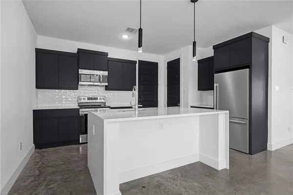 a kitchen with stainless steel appliances a refrigerator and a stove top oven