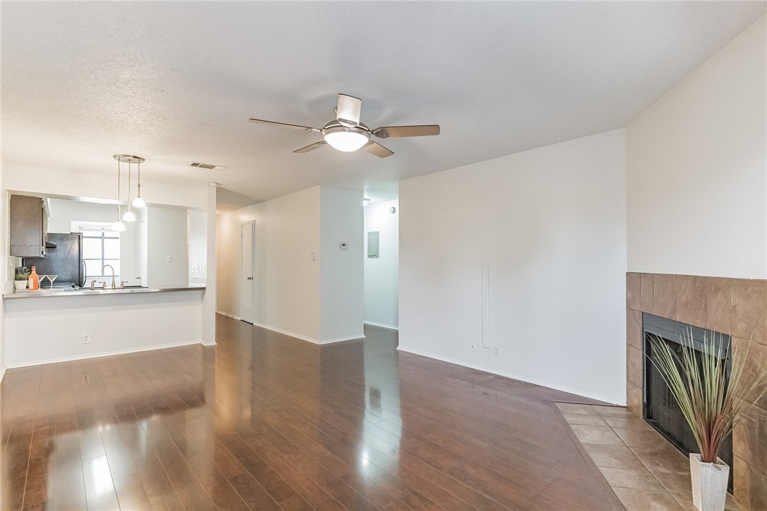a view of a livingroom with a fireplace a ceiling fan and wooden floor