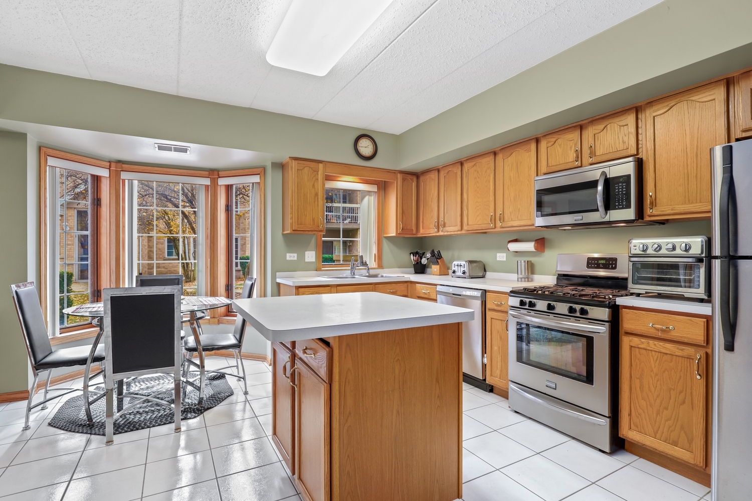 7825 Bristol Park Drive, Unit 1C Tinley Park, IL 60477 - Photo 8 of 22 a kitchen with stainless steel appliances granite countertop a stove top oven a sink dishwasher a dining table and chairs with wooden floor