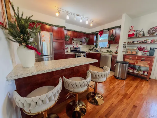 a kitchen with stainless steel appliances kitchen island granite countertop a sink a refrigerator and a stove