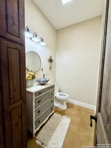a bathroom with a granite countertop toilet sink and mirror