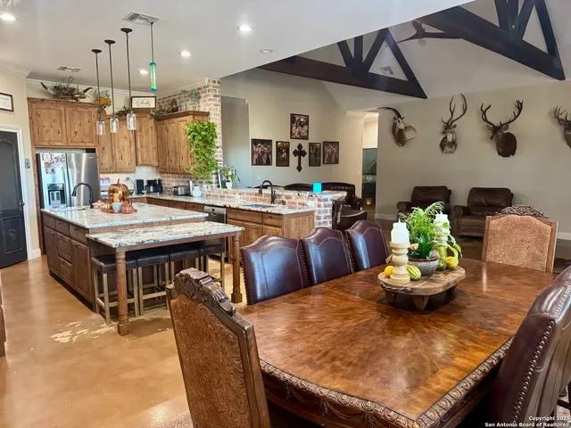 a kitchen with stainless steel appliances kitchen island granite countertop a table chairs and a refrigerator