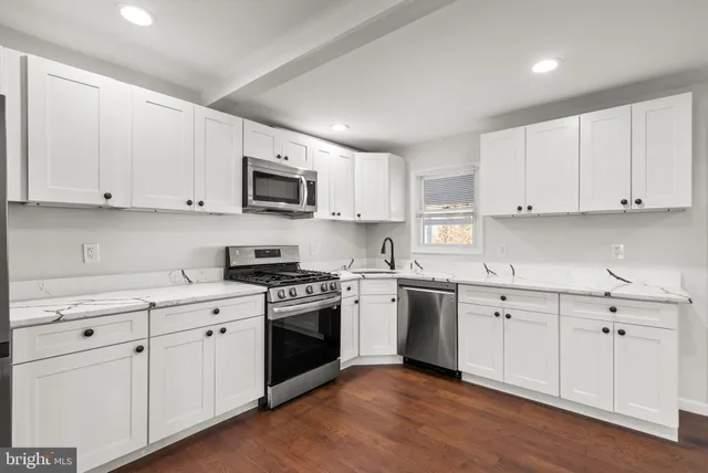 a kitchen with cabinets stainless steel appliances a sink and wooden floor