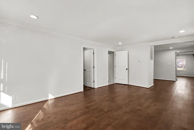 a view of an empty room with wooden floor & window