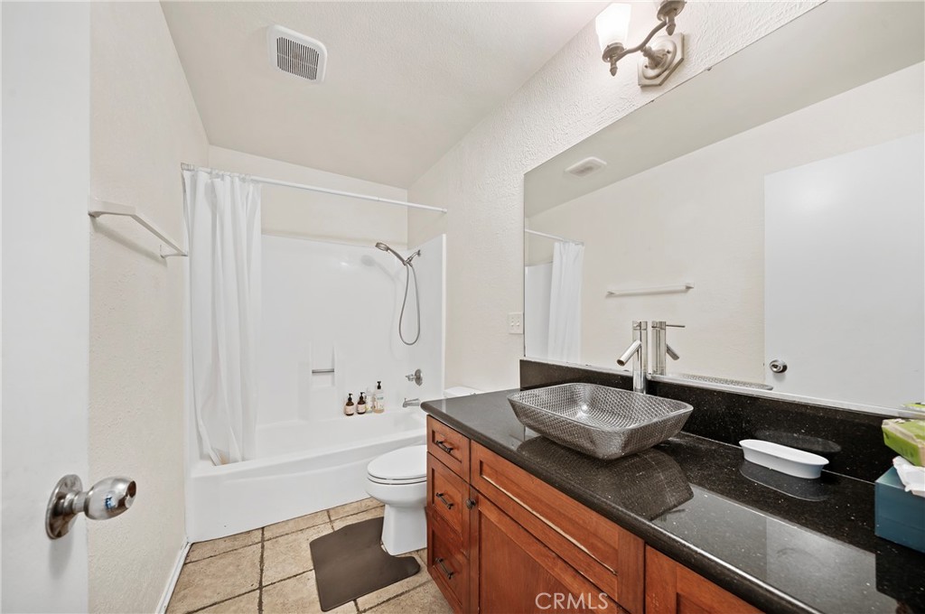63 Streamwood Irvine, CA 92620 - Photo 19 of 25 a bathroom with a granite countertop sink a toilet a mirror and shower