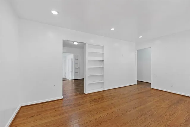 a view of an empty room with wooden floor and closet