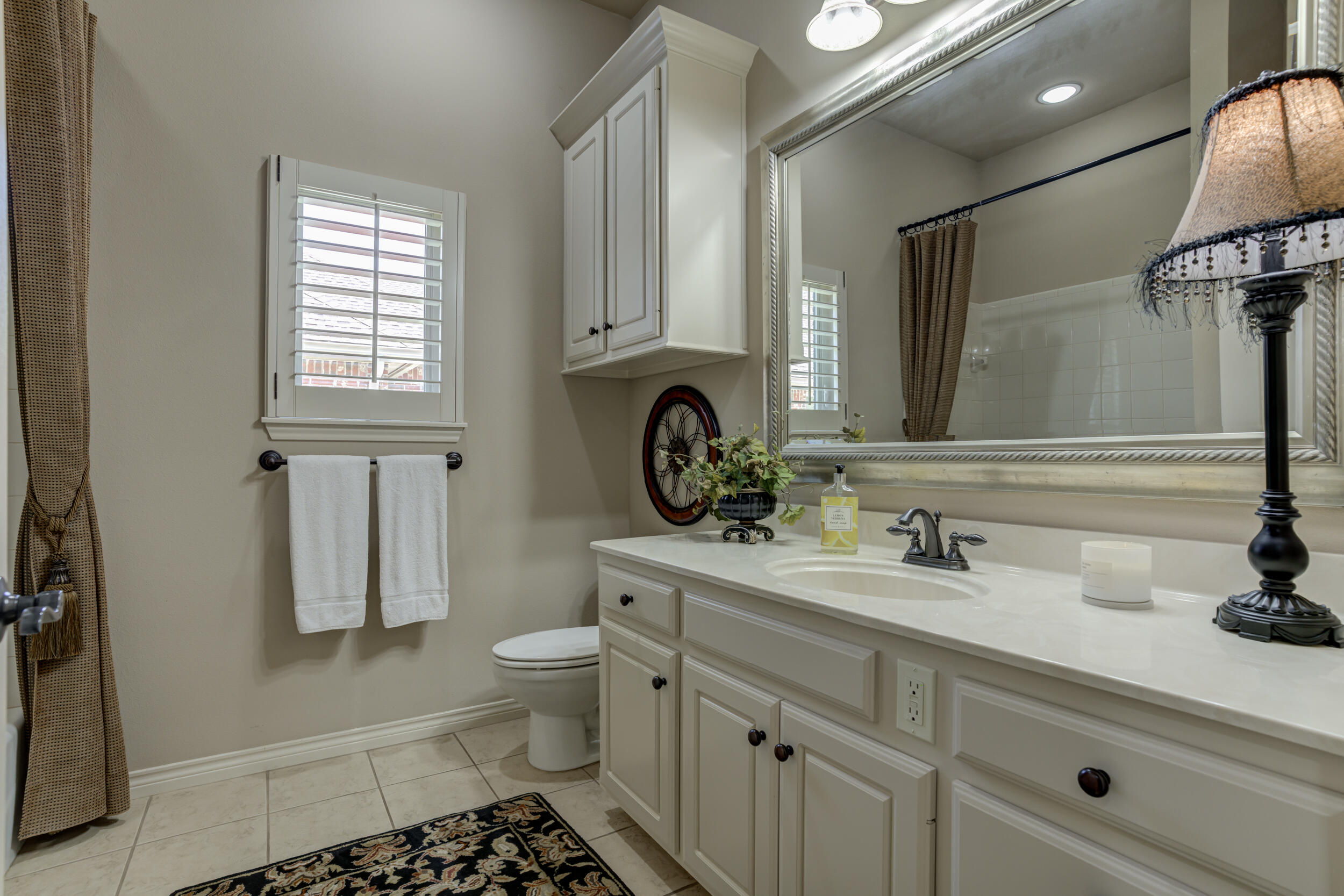 6008 89th Street Lubbock, TX 79424 - Photo 46 of 61 a bathroom with a sink a toilet and a mirror