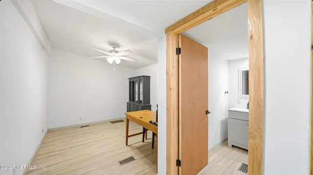 a view of a hallway with wooden floor and a bathroom