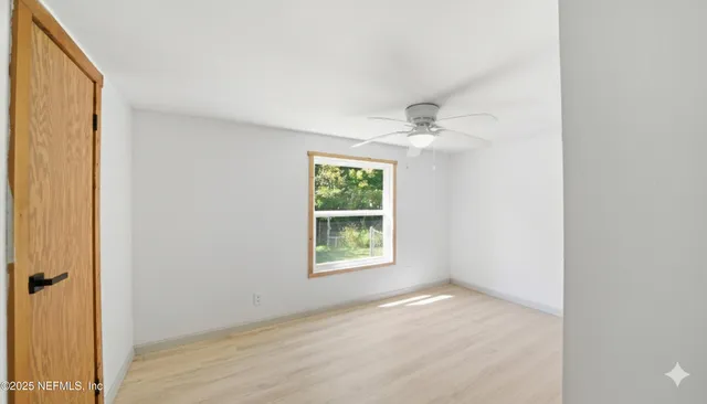 an empty room with windows and a ceiling fan