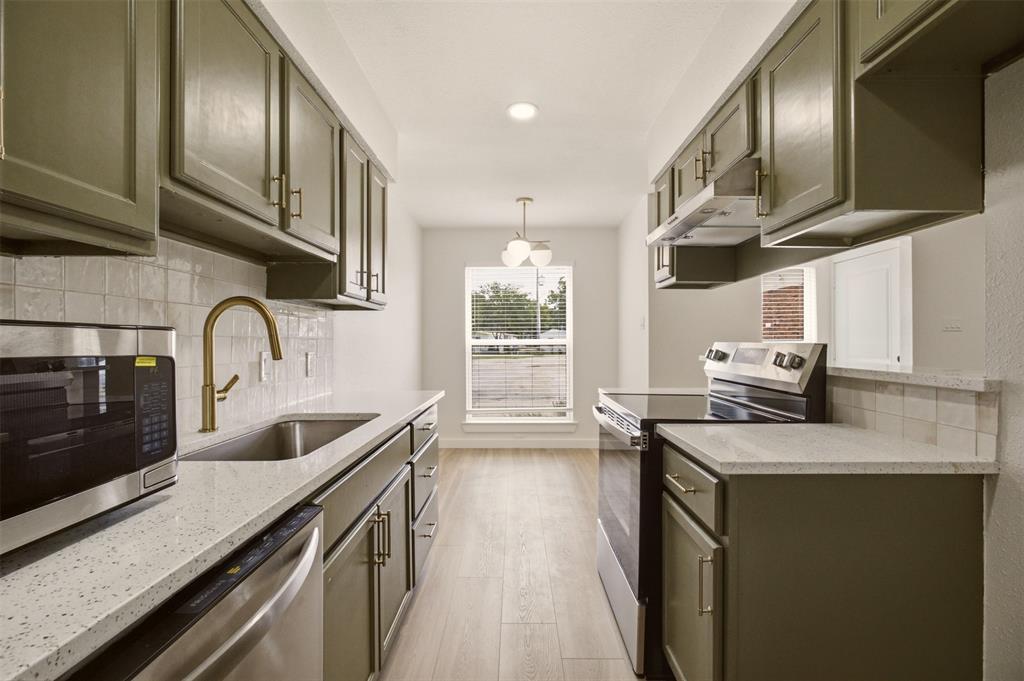 908 Isbell Road, Unit A Fort Worth, TX 76114 - Photo 7 of 28 Galley kitchen featuring sage green cabinetry, light speckled countertops, a tile backsplash, and light wood-finish flooring