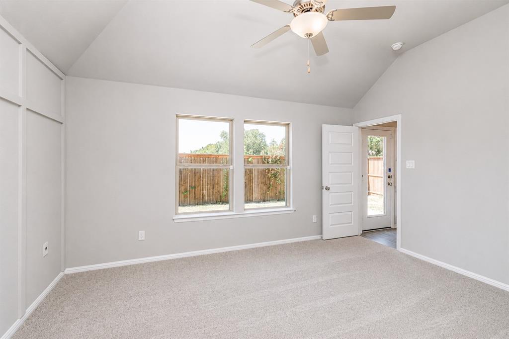 3344 Duncan Way Corinth, TX 76210 - Photo 15 of 38 Vaulted ceiling with a ceiling fan, two windows, carpet flooring, board and batten wall accent, and a door providing exterior access