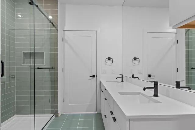 a bathroom with a double vanity sink a mirror and shower